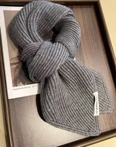 Close-up of a cozy gray chunky knit scarf neatly displayed on a tray for warm winter style.