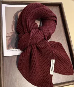 Close-up detail of the cozy burgundy knitted winter scarf, showing soft wool texture.