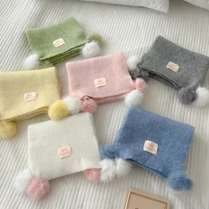 Cute knitted winter scarf with fluffy pom poms and bow label for cozy and warm daily wear.