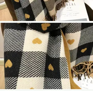 Close-up detail of winter cozy black and white plaid scarf with cute golden heart pattern.