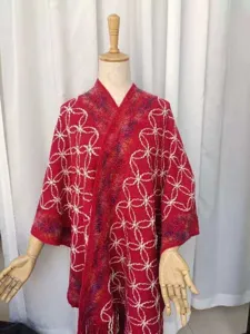 Vista dettagliata dello scialle in maglia rossa con motivo a trifoglio e bordo colorato.