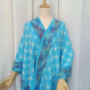 Mantella poncho in maglia blu con motivo a trifoglio, ideale per outfit di viaggio estivi.