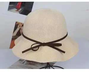 Nahaufnahme des beigen Strick-Fischerhuts mit brauner Schleife, ideal für den Sommer.