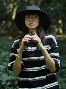 Outdoor detail shot featuring a black drawstring bucket hat worn by a model in forest setting.