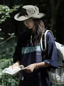 Outdoor camping hat detail shot, showing the stylish grey bucket hat worn by model in nature.