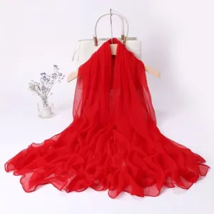 Detail view of a bright red long women's scarf draped on a white hanger with bag decor.