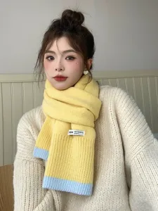 Gros plan détail de cette écharpe en tricot jaune douillette avec une petite étiquette.