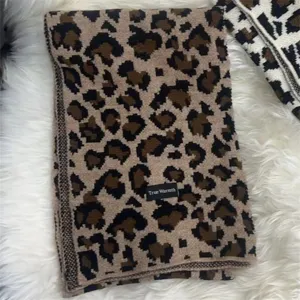 Close-up detail of cozy leopard print knitted winter scarf with brand tag texture.