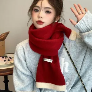 Écharpe en tricot rouge confortable avec ourlet beige, accessoire d'hiver élégant pour femmes.