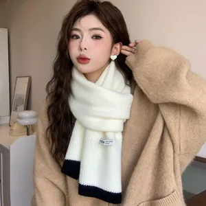 Gros-plan sur une écharpe en tricot blanc doux avec des extrémités noires et cosy.