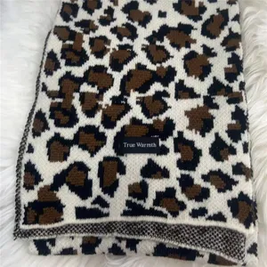 Close-up detail of a soft knit winter scarf with classic brown and black leopard print pattern.