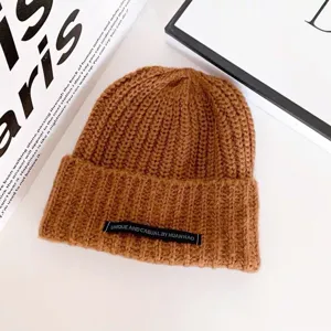 Braune Strickmütze Detailansicht mit weicher Wolle Textur und einzigartigem Mode Buchstabenetikett.