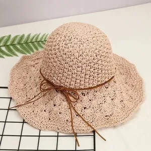 Nahaufnahme des handgemachten Strohhuts mit brauner Schleife, ideal für den Sommer am Strand.