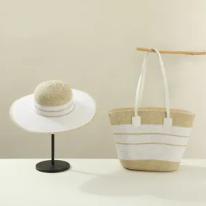 Detailed shot of summer straw hat and woven handbag set with beige and white stripes.