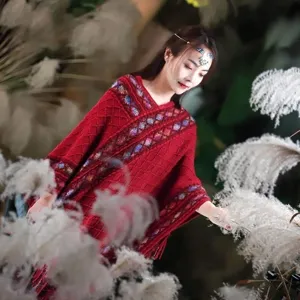 Red knit tassel poncho detail shot, comfortable casual outdoor vacation shawl style, warm cape design.