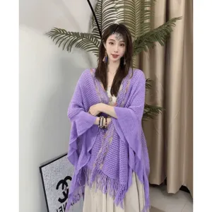 Vue détaillée de la cape en tricot violette avec franges portée par le mannequin en intérieur