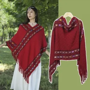 Detailed view of the red knitted cape with fringe and geometric patterned band design.