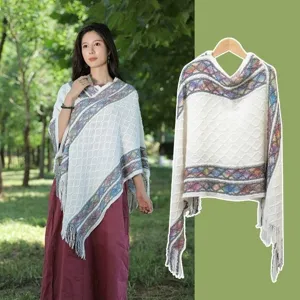 Outdoor vacation knitted poncho with colorful geometric borders and tassels for travel.