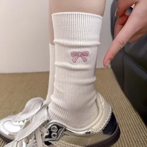 Detail view of white cotton mid-tube socks featuring cute pink embroidered bow design.