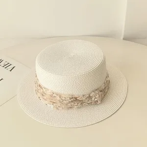 Nahaufnahme des Strohhutes mit flacher Krone und einem schicken Blumen-Chiffonband.
