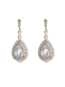 Détail de boucles d'oreilles pendantes en cristal doré en forme de poire avec perle.