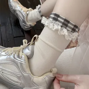 Gros plan détaillé de chaussettes mi-mollet à carreaux gris et bleu avec bordure en dentelle.