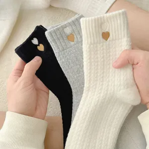 Detailed shot of thick winter warm mid-tube socks with cute embroidered heart patterns.