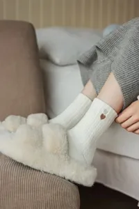 Cozy winter socks detail shot featuring soft ribbed knit fabric and cute embroidered heart.