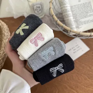 Detailed shot of rolled ribbed socks featuring delicate embroidered bow accents in multi colors.
