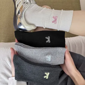 Close-up detail shot of cute ribbed bow embroidered cotton socks in various chic colors.