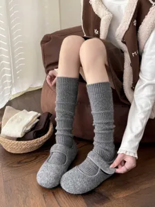 Detailed view of grey knit mid-calf socks and matching casual shoes in cozy indoor setting.