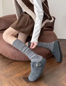 Detailed view of cozy grey knitted calf socks worn with casual clogs, warm winter leg warmers.