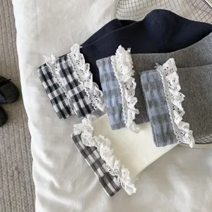 Détail de chaussettes mi-mollet à carreaux rétro pour femmes avec bordure en dentelle blanche.