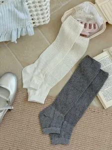 Gros plan détaillé de chaussettes montantes côtelées à rayures verticales en blanc et gris.