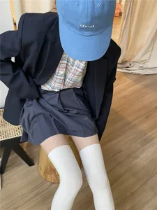 Detail shot of white ribbed over-the-knee socks paired with casual outfit on wooden floor.