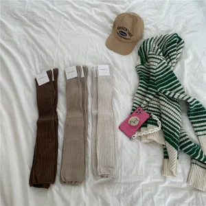 Detailed view of ribbed over-the-knee socks in neutral colors laid flat with cozy accessories.