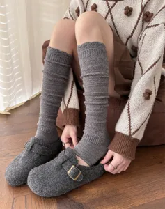 Close-up detail of grey knitted stirrup leg warmers paired with wool felt clogs for winter.
