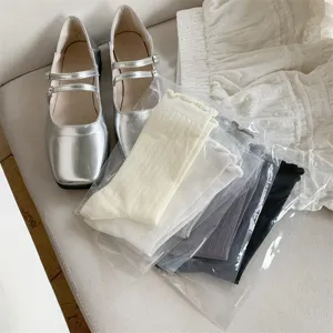 Silver Mary Jane shoes and packaged ruffle socks paired with white fabric for daily detail view.