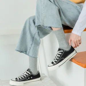 Nahaufnahme grauer mittelhoher Socken kombiniert mit Freizeitschuhen im modernen Alltag.