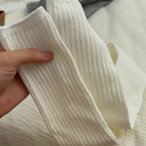 White ribbed knit long slouch socks detail showcasing soft textured fabric and elastic cuff.