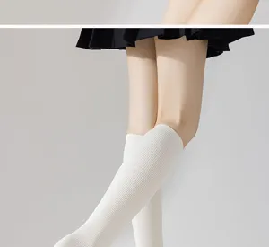 Close-up view of white ribbed knee-high socks showing textured knit fabric and fit.