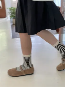 Gedetailleerd overzicht van gestreepte dameskousen gecombineerd met retro schoenen.