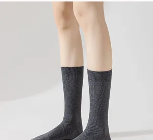 Detail view of dark grey ribbed mid-calf socks worn by a model, comfortable everyday wear.