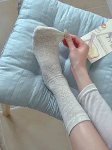 Detail shot of women's white mesh lace pattern socks, showing elasticity and breathable fabric.