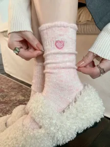 Primo piano di calze spesse in lana con ricamo a cuore e tessitura a coste, stile accogliente.