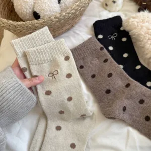 Close-up of winter thick warm knit socks with cute polka dots and delicate bow embroidery details.