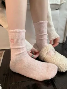 Primo piano dettagliato di comodi calzini slouch in lana rosa a coste, logo a cuore.