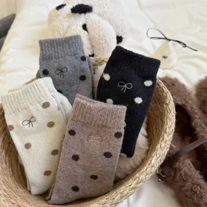 Warm winter wool socks with cute polka dots and embroidered bow details in a cozy basket.