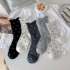 Close-up detail shot of cute bow print stackable mid-tube socks in versatile neutral colors.
