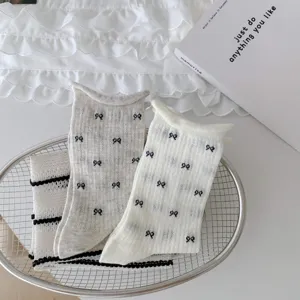 Detailed shot of women thin rolled edge socks with cute tiny black bow patterns in basket.